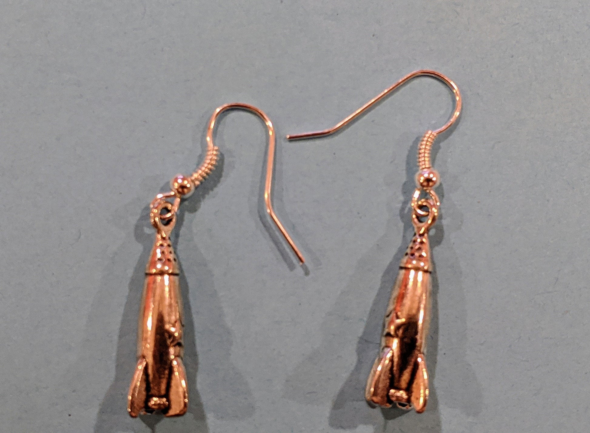 Close up of silver toned rocketship dangle earrings showing the details