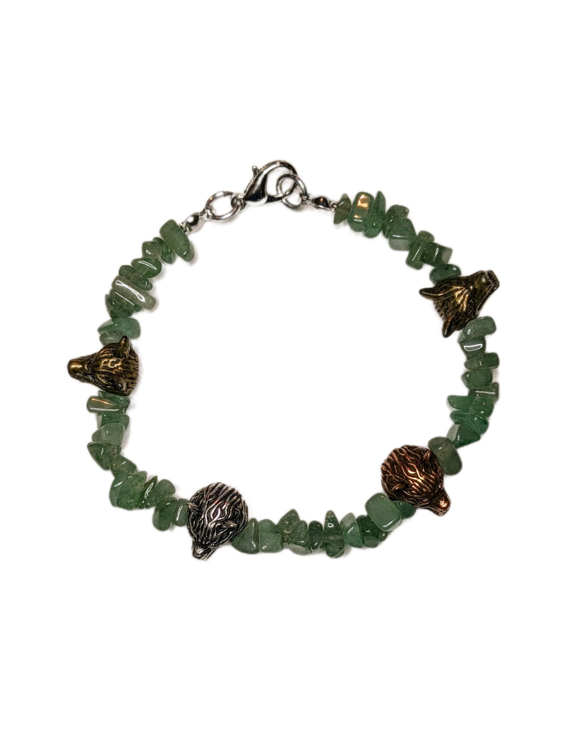 A bracelet made of green aventurine chip beads and metal wolf head shaped bead accents.