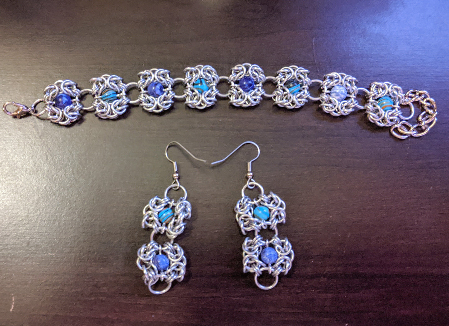 Romanov chainmail bracelet and earrings with dyed malachite beads on a desk