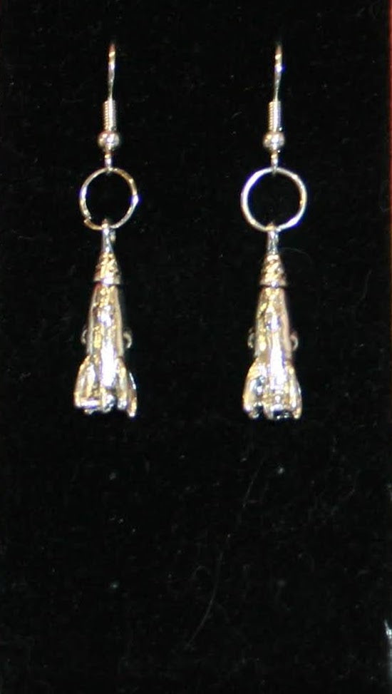 A pair of shiny silver rocket-shaped earrings against a black background.