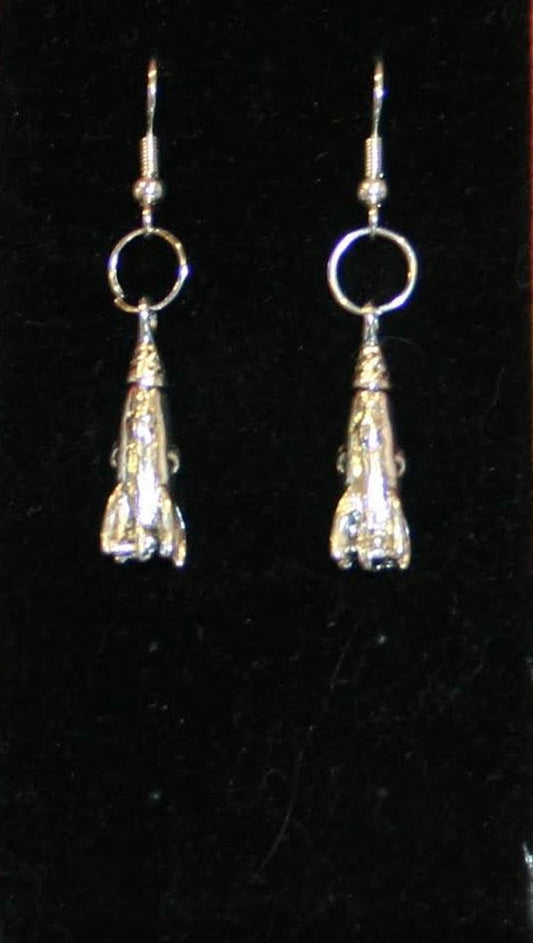 A pair of shiny silver rocket-shaped earrings against a black background.