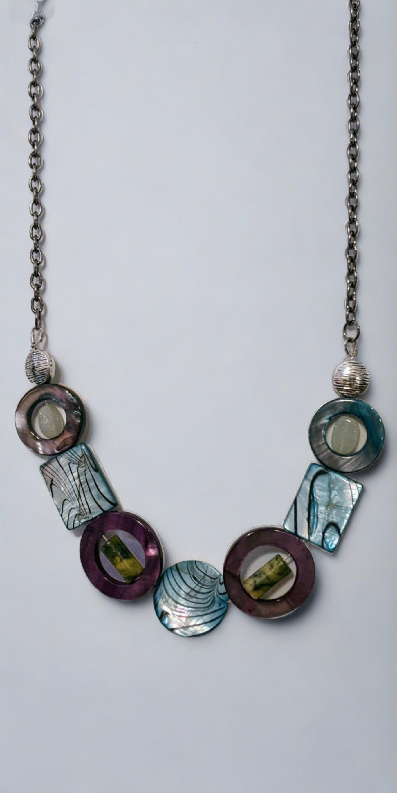 Linked component necklace on a white background. The wire wrapped links are of grey marble canyon and dyed shell alternating. The center is a round marble canyon bead and the other beads are rectangular.