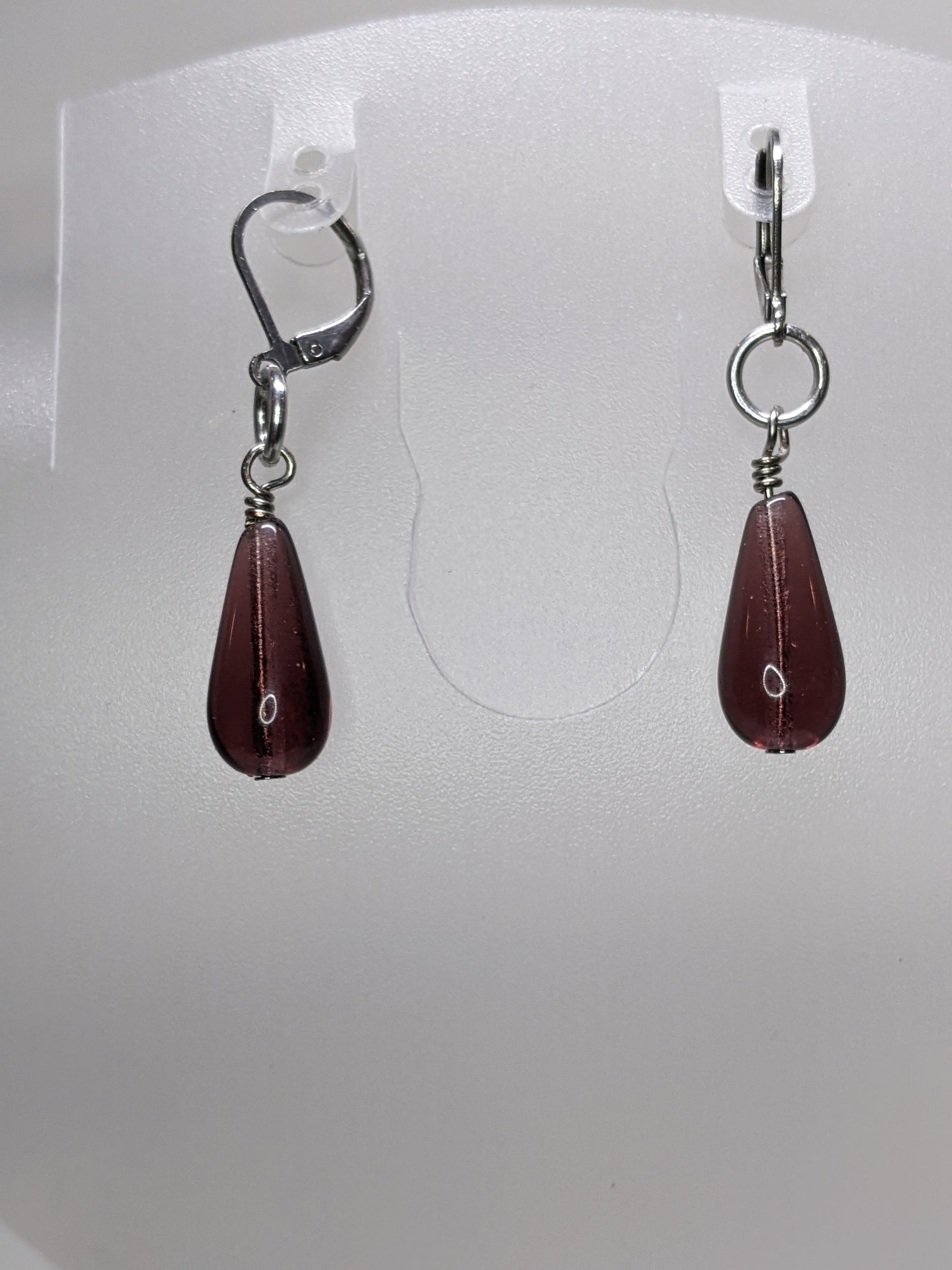 Purple teardrop earrings on a white display