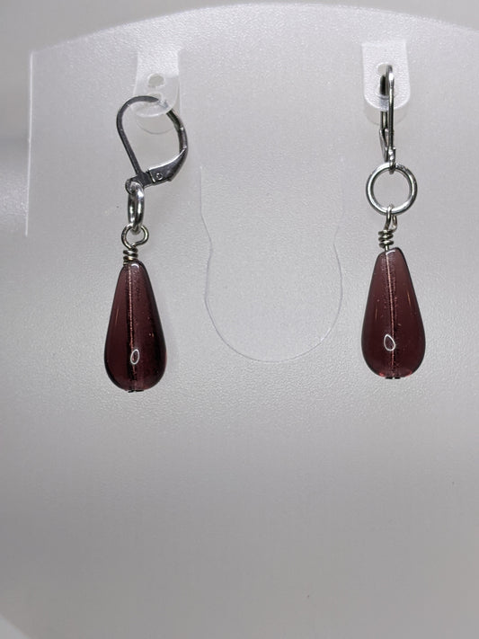 Purple teardrop earrings on a white display