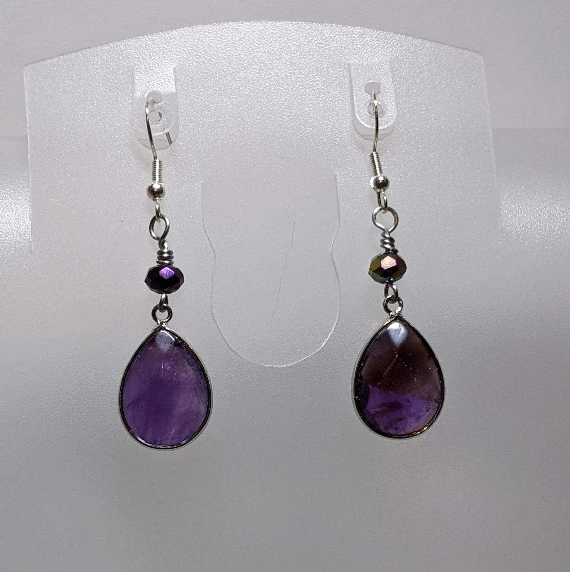 A pair of purple drop earrings with faceted beads, displayed against a white background.