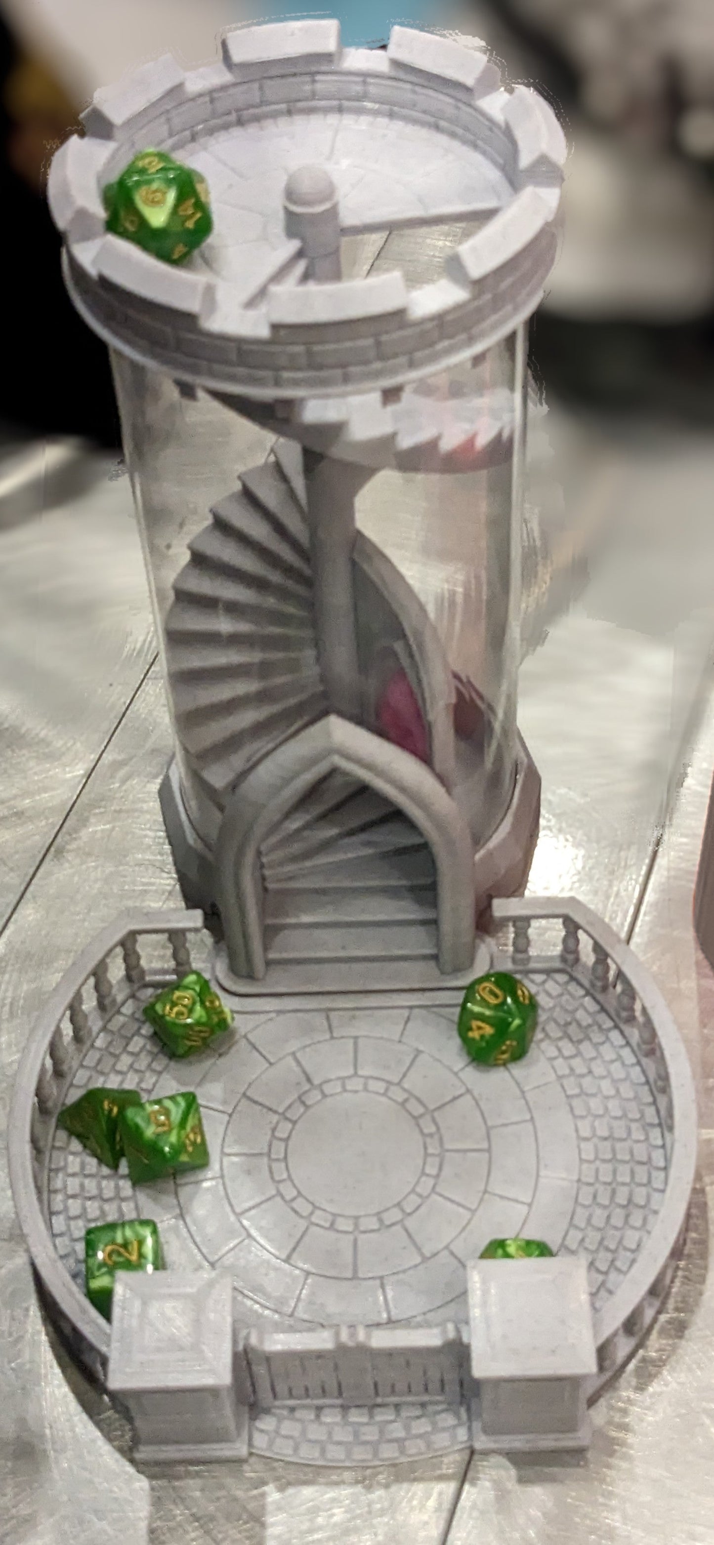 3D printed dice tower and tray in the shape of a castle tower and courtyard. A set of green and yellow dice sit in the tray with the D20 on top of the tower waiting to roll.