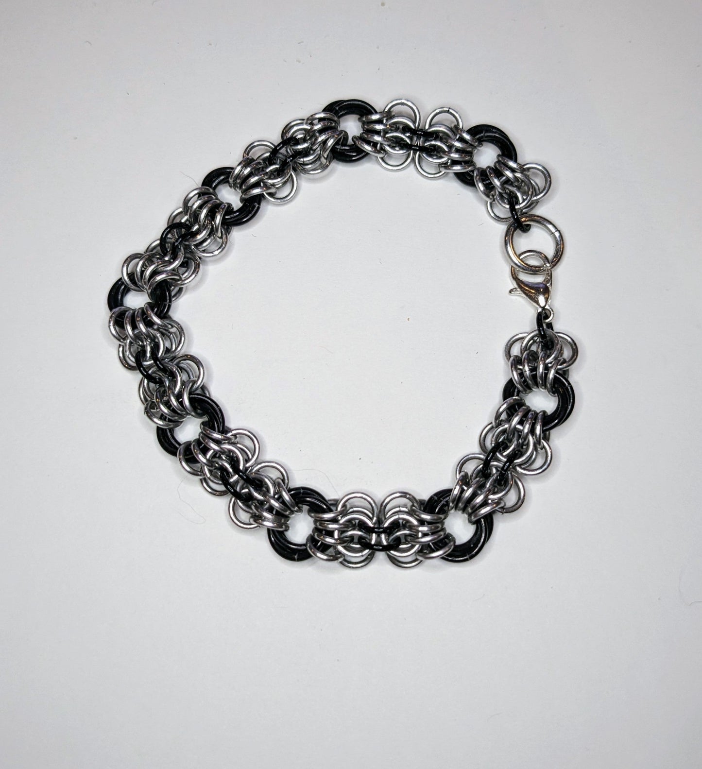 Silver and black butterfly weave chainmail bracelet on a white background. Bracelet has a lobster clasp.