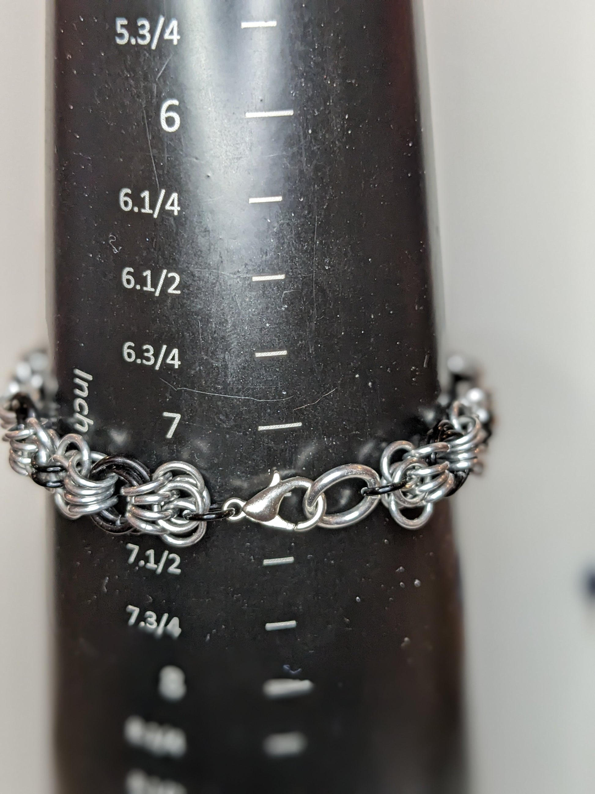 Silver and black butterfly weave chainmail bracelet on a black mandrel showing bracelet is 7.25 inches
