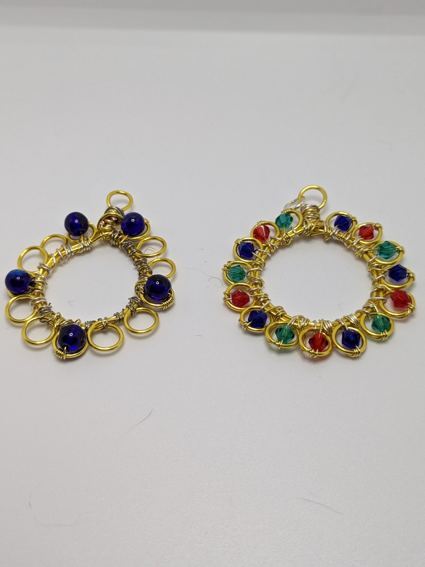 Two wire wrapped and beaded pendants on a white background