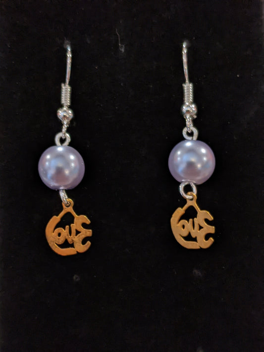 A pair of drop earrings featuring gold-colored cut-out charms that say love and pearl beads.