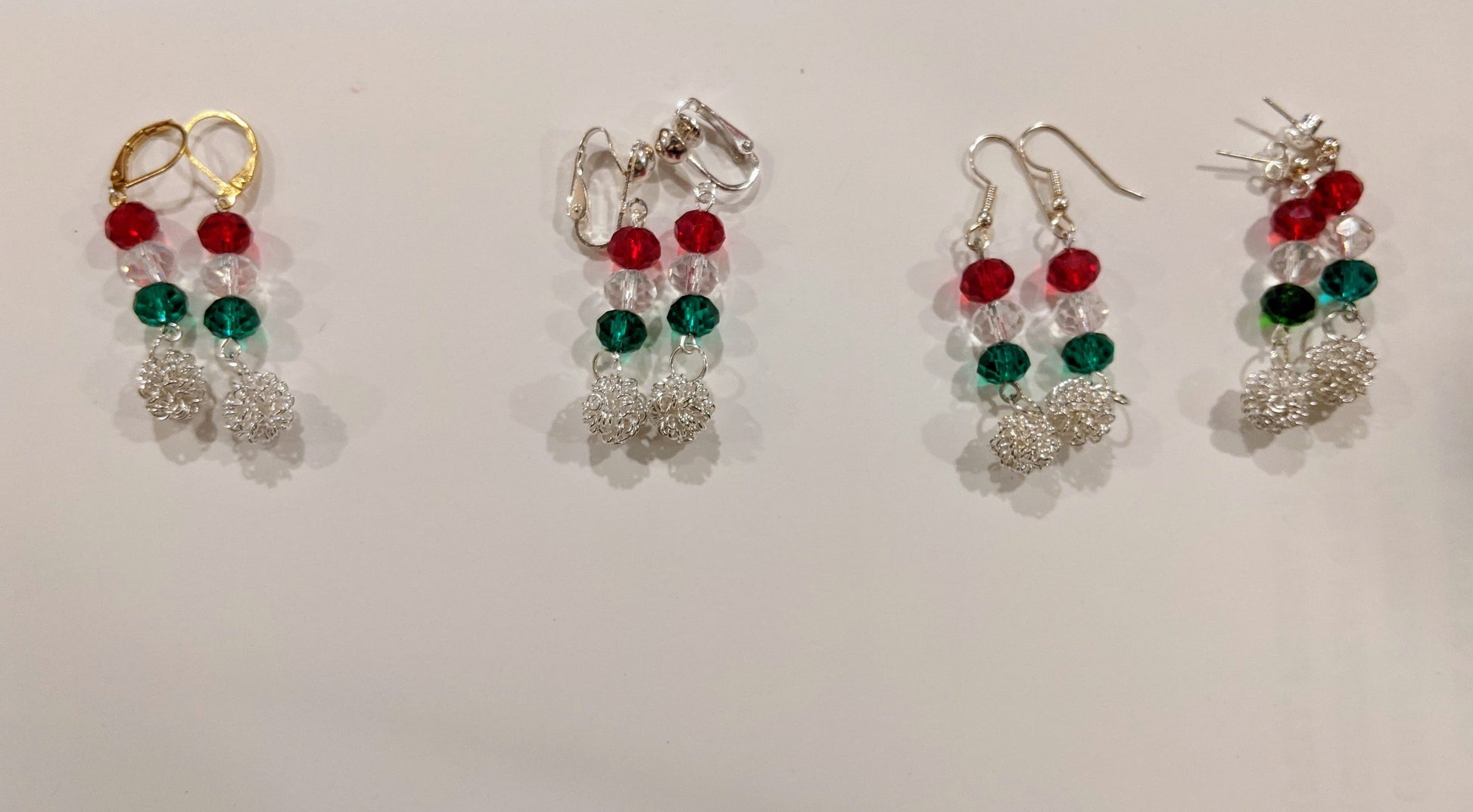 A collection of festive dangle earrings with silver chain and multicolored glass beads displayed against a white background.