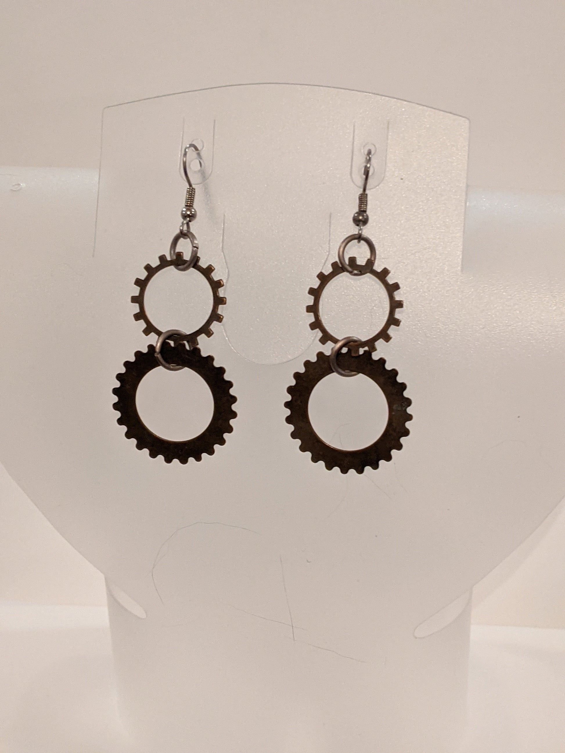 A pair of dangle earrings with intricate steampunk-style gear designs.