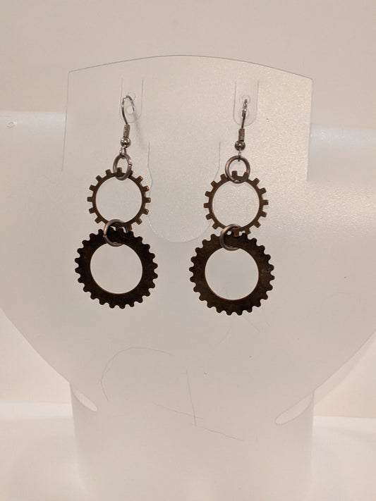A pair of dangle earrings with intricate steampunk-style gear designs.