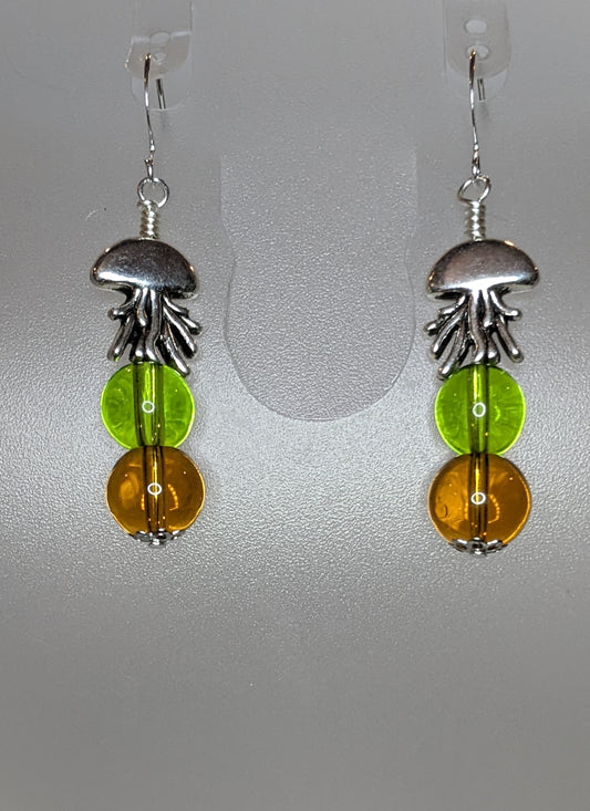 A pair of earrings featuring silver jellyfish shapes with clear topaz and green round glass beads attached to silver plated ear wires.