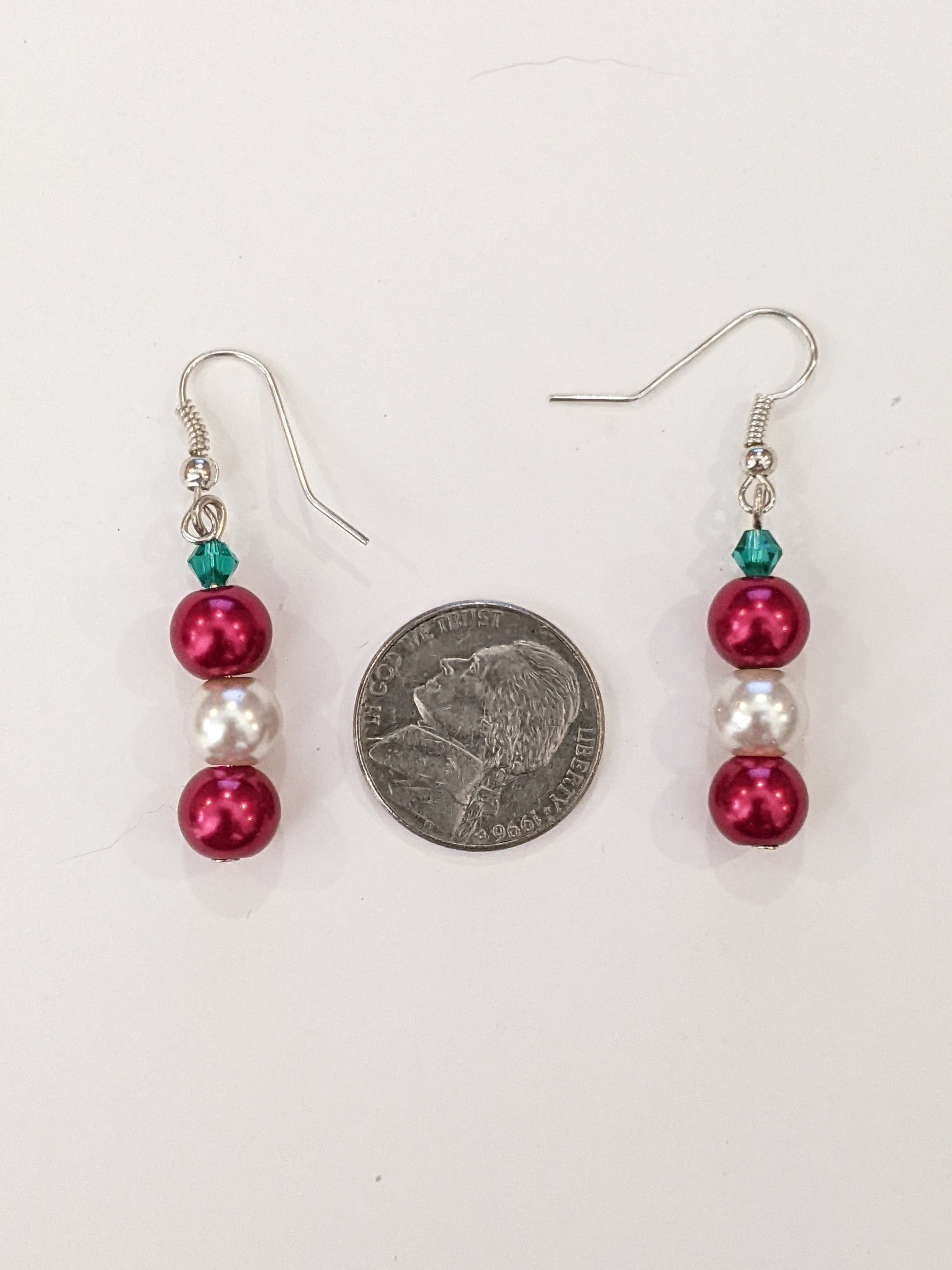 A pair of pearl bead dangle earrings with red and white glass pearls and green faceted bicone, on silver French hook ear wires  with a nickel between showing size.