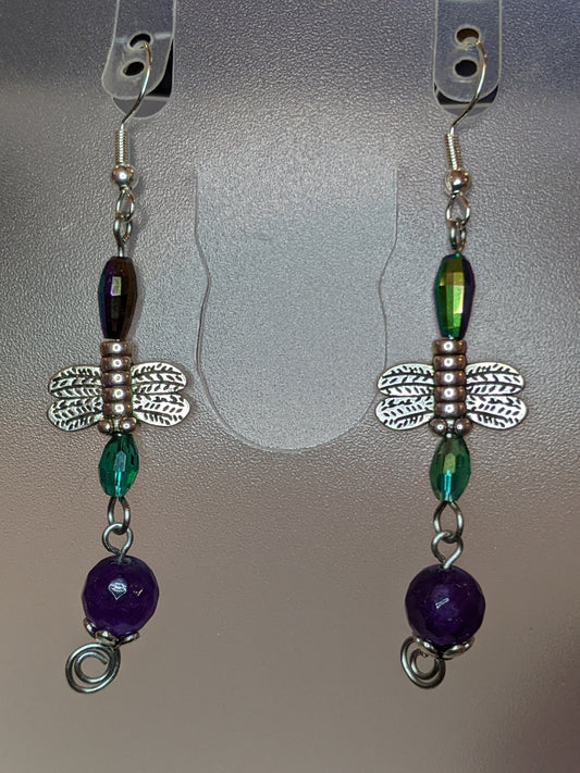 A pair of beaded dangle earrings featuring purple and green beads with silver-colored dragonfly charms.