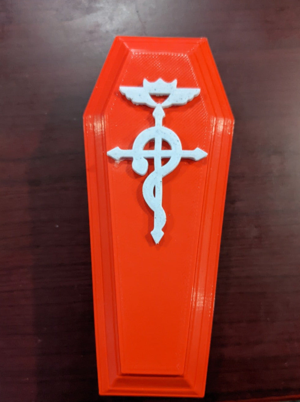 Red coffin shaped dice/trinket box with white alchemy symbol