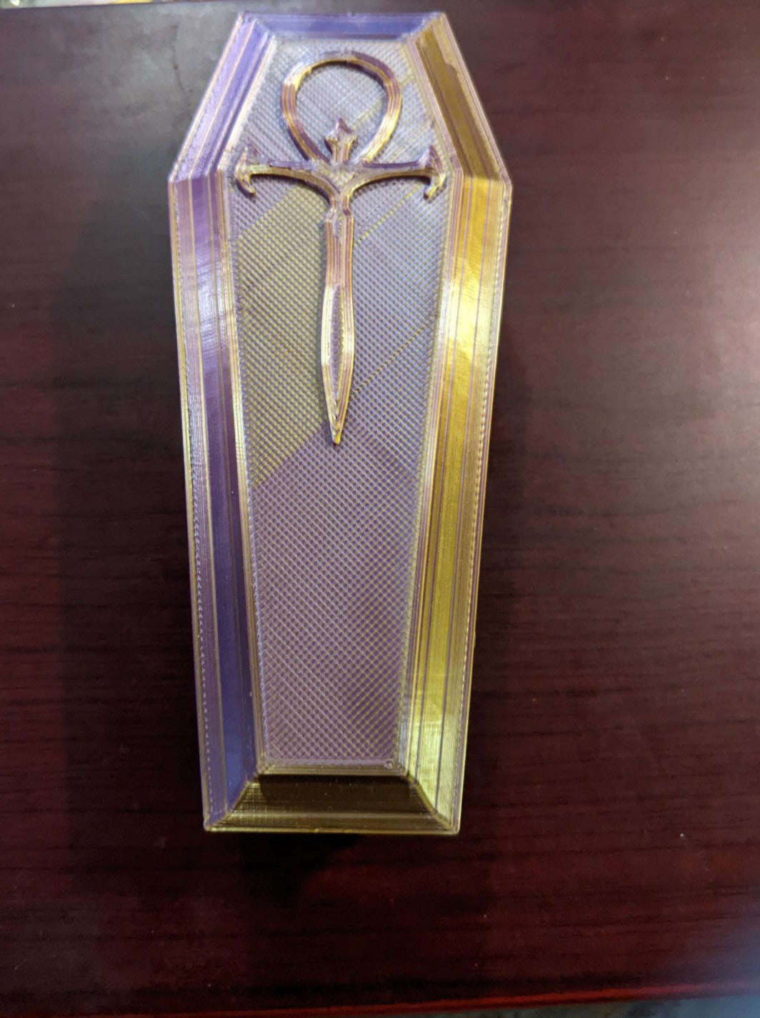 Close up of a coffin shaped trinket/dice box with a modified ankh decoration