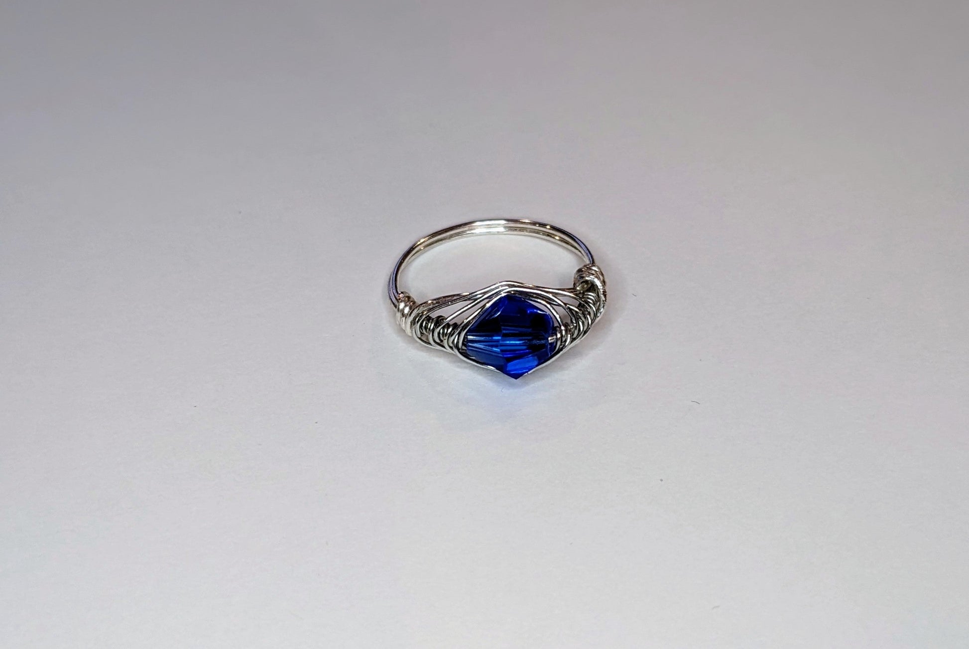 Silver wire wrapped ring with a blue stone on a white background