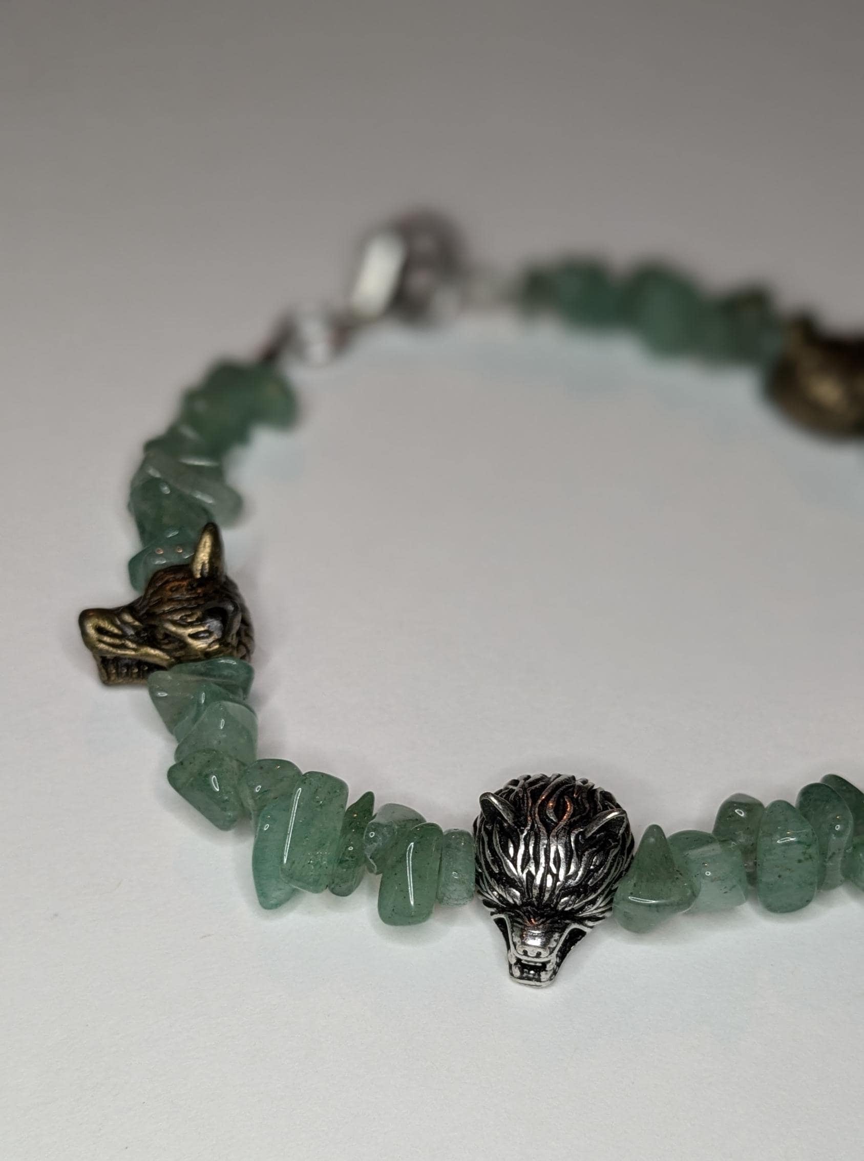 A bracelet made of green aventurine chip beads and metal wolf head shaped bead accents.