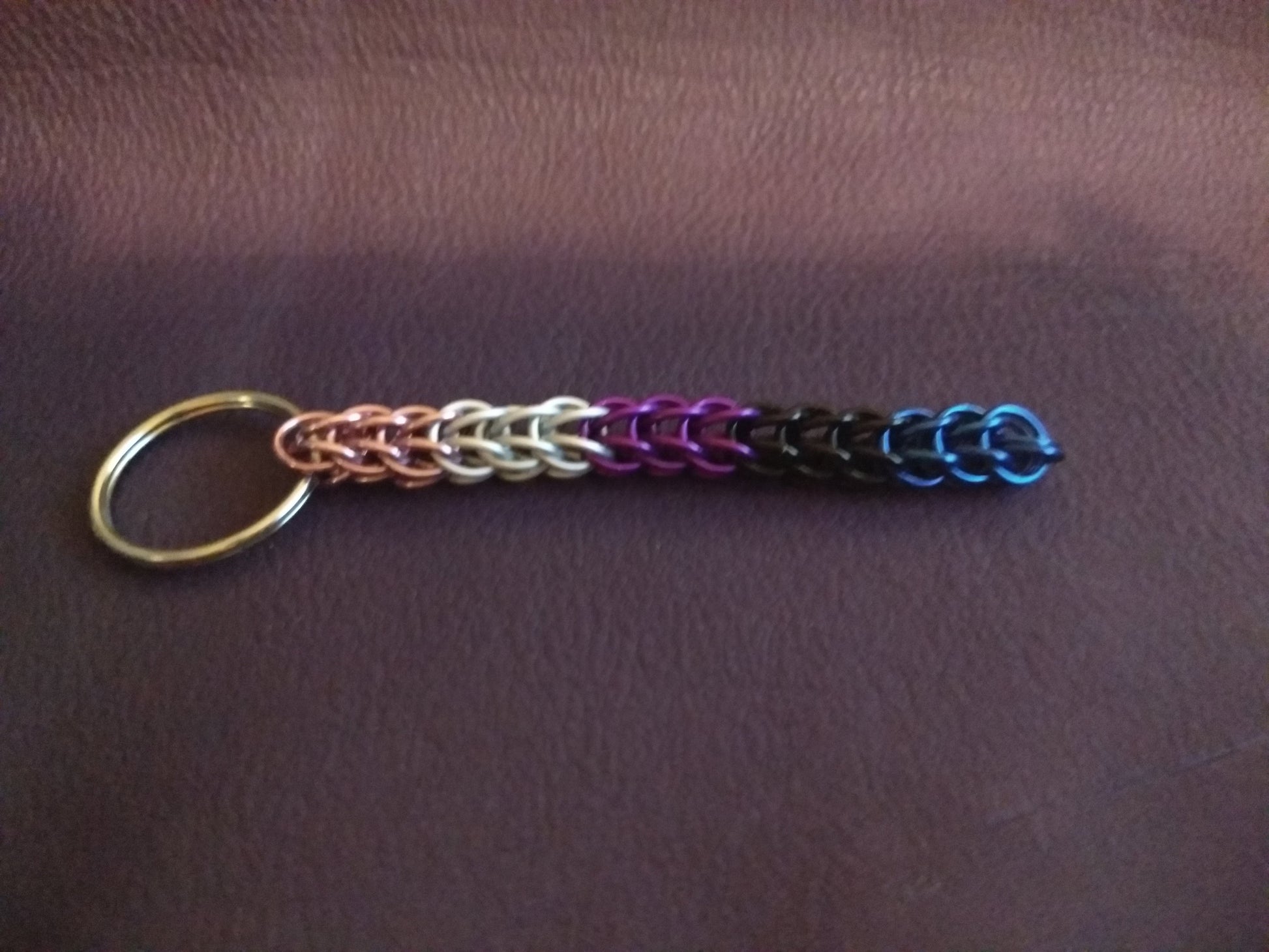 Chainmail keychain in Genderfluid pride colors on a dark purple background