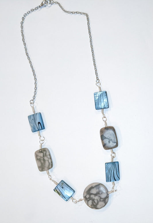 Linked component necklace on a white background. The wire wrapped links are of grey marble canyon and dyed shell alternating. The center is a round marble canyon bead and the other beads are rectangular.