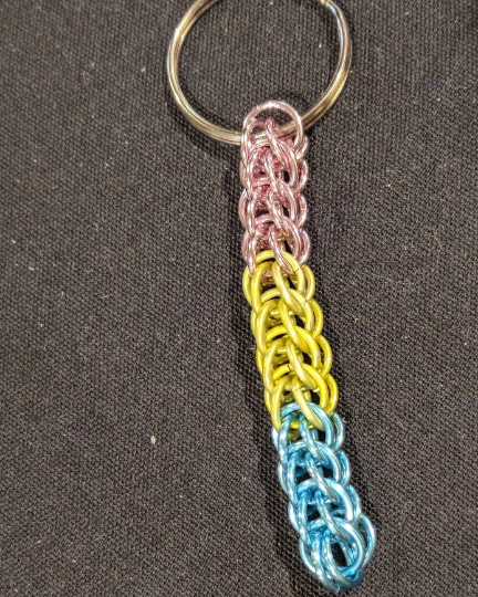 Chainmail keychain with split ring in pansexual flag colors on a dark background