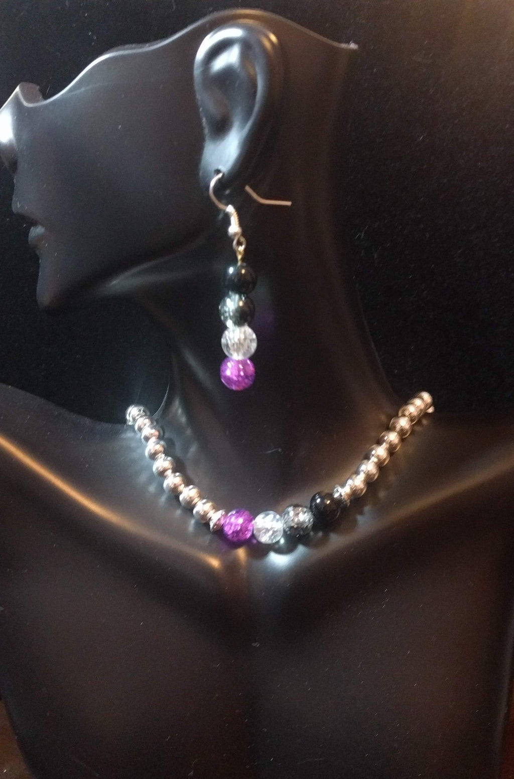 A beaded jewelry set displayed on a mannequin, consisting of a necklace and earrings with asexual pride color accent beads.