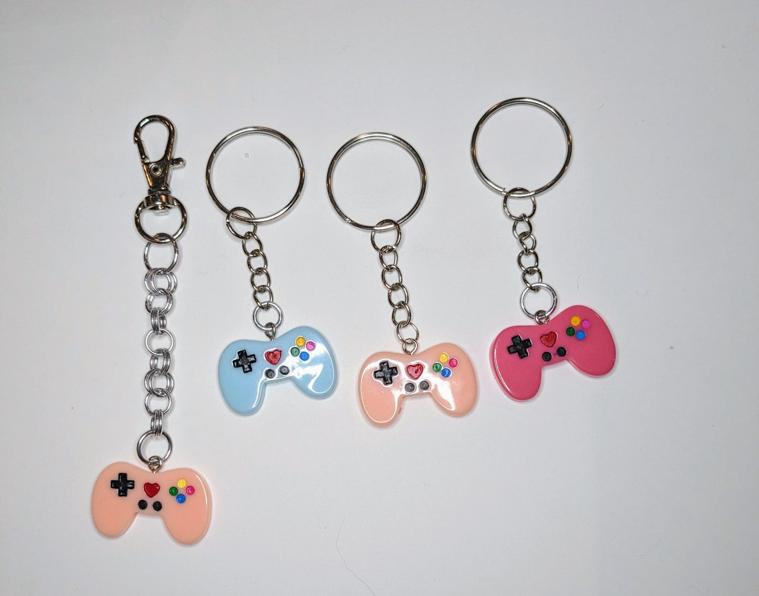 A set of colorful game controller keychains on a keyring, with each controller featuring a unique color and design.