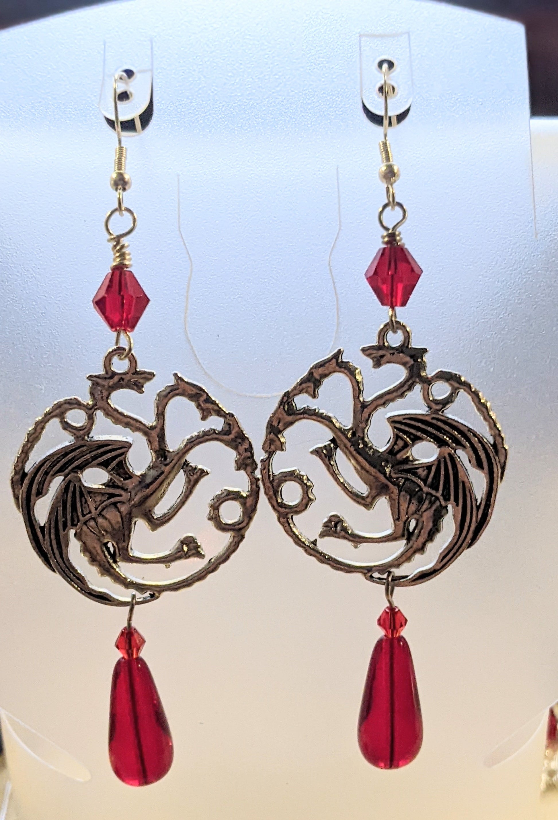 Silver circular three headed dragons accented with red crystal faceted bicone beads with red Czech glass teardrop at the bottom 