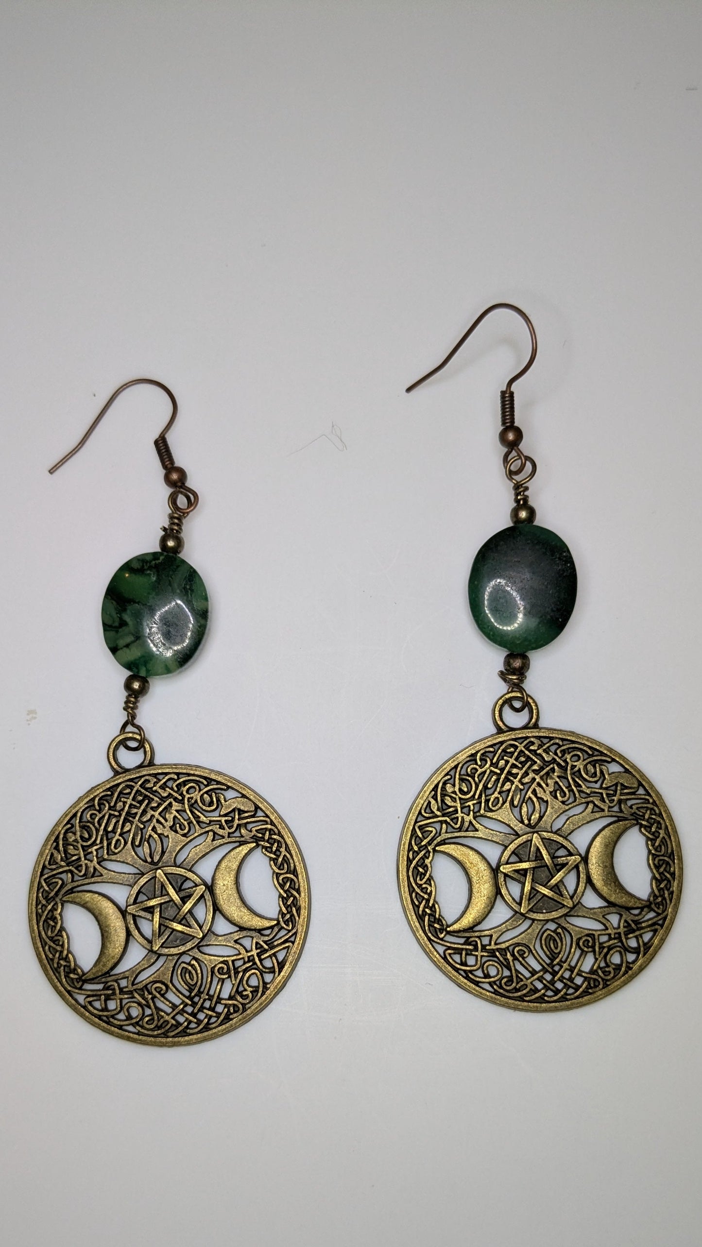 Pair of earrings with green beads and gold designs on a white background